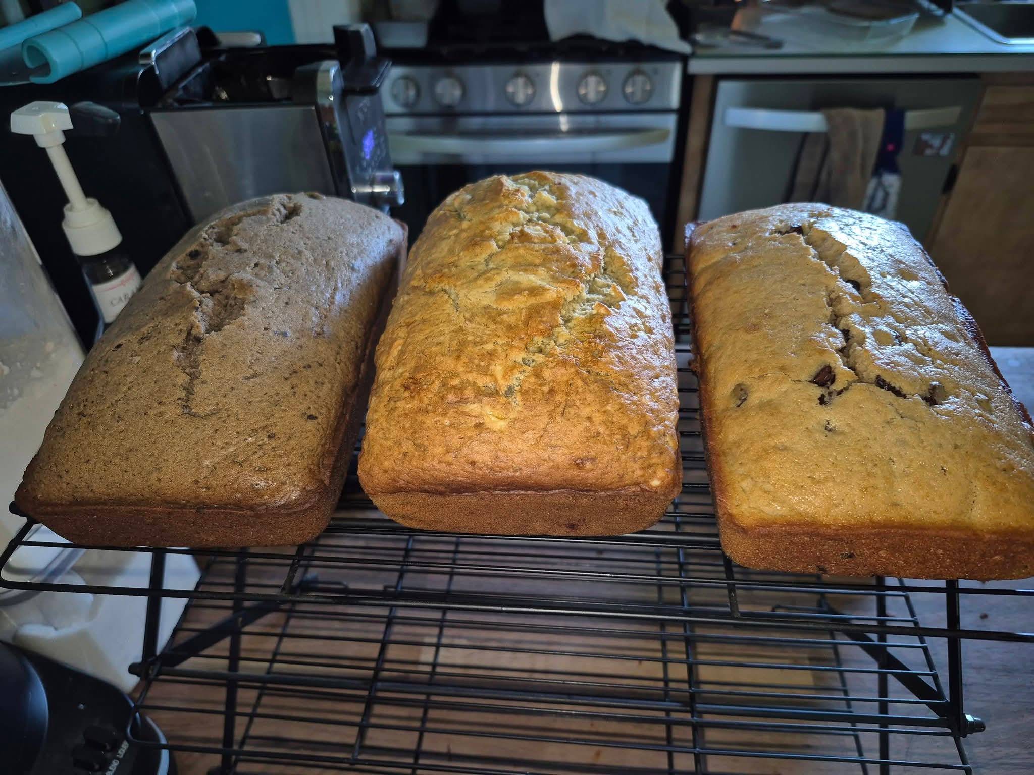 Three fresh-baked homemade bread loaves cooling on a wire rack