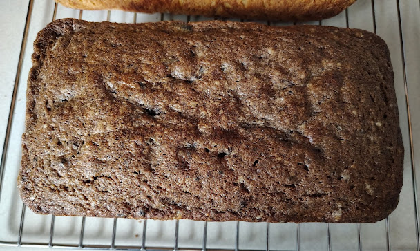 A dark, rich homemade loaf cooling on a wire rack